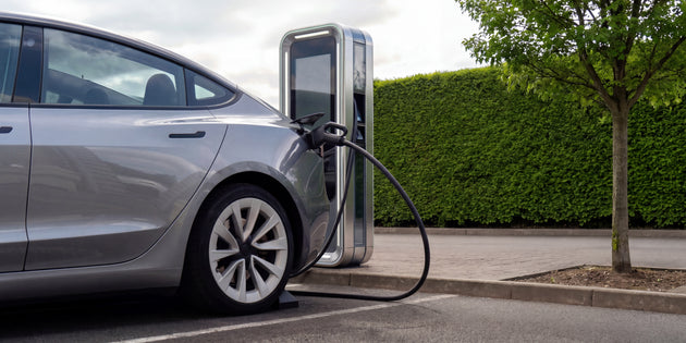 Silver electric car connected to a CCS2 rapid charging station at a roadside DC fast charging point