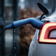 Blue charging plug in the rain against the illuminated rear light of a car