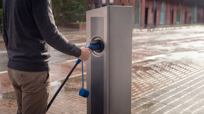 Man plugging a blue Voldt Type 2 EV charging cable into a public charging pole